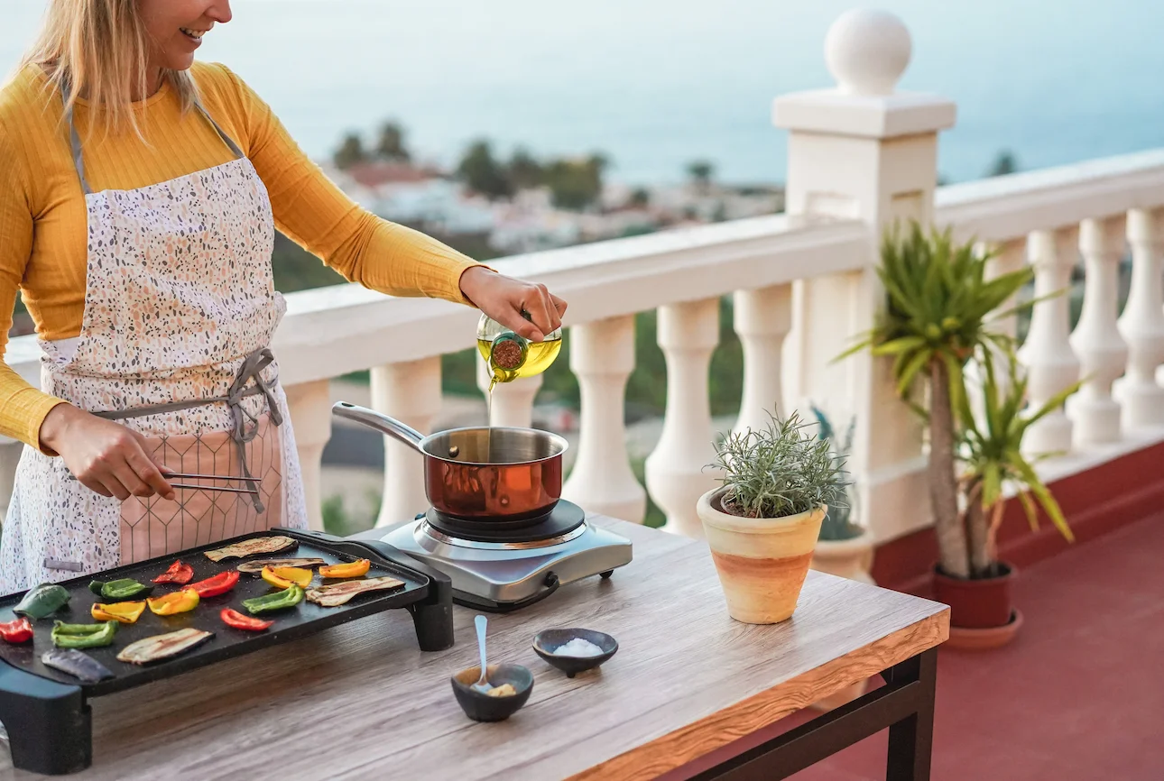 Woman grilling vegetables outdoors showing a simple cooking method that uses less oil and added fats