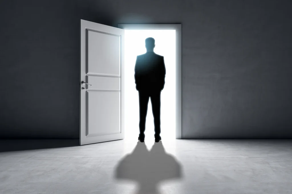 Businessman standing before a bright doorway representing opportunity and change