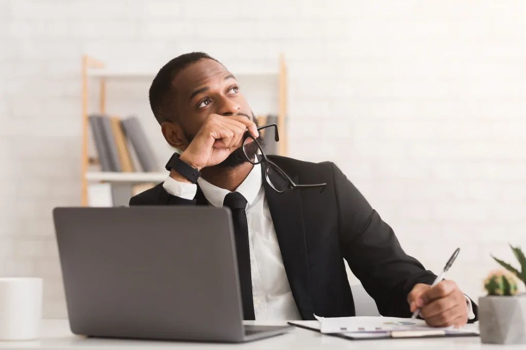 Pensive businessman sitting at a desk and reflecting on a business plan