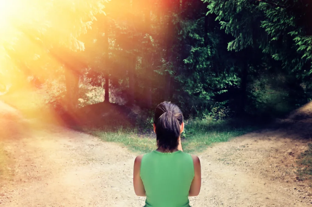 Woman standing at a forked road symbolizing different choices and directions in life